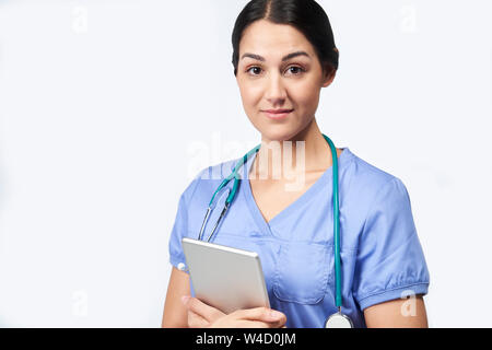 Studio Portrait Of Female Nurse Wearing Scrubs Holding Digital Tablet Stock Photo