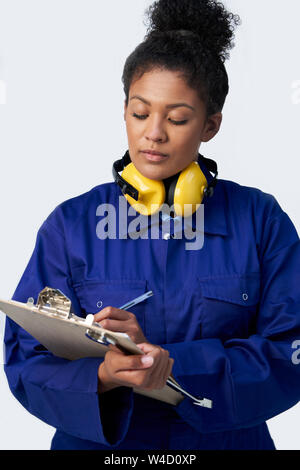 Studio Shot Of Female Engineer With Clipboard And Spanner Against White Background Stock Photo