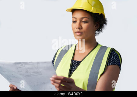 Studio Shot Of Female Architect With Studying Plans Against White Background Stock Photo