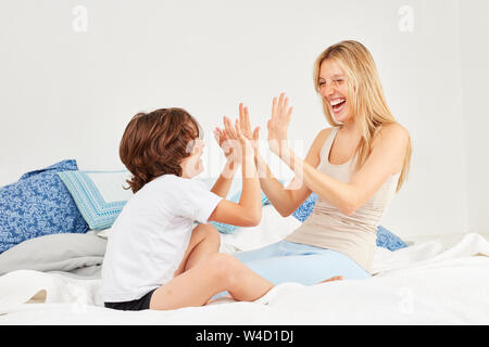 Boy playing with his mother on the bed a cheerful gossip Stock Photo