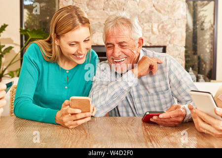 Woman shows senior a text message on the smartphone or explains the social media Stock Photo