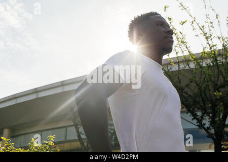 African American man with hands on hips pose looking to the sky at home. Young guy in white shirt thinking and looking to the future Stock Photo