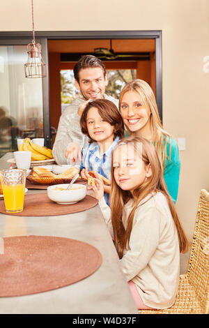 Family with two kids having breakfast together in the kitchen in the morning Stock Photo