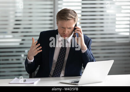 Angry frustrated businessman talking on phone solving business problem Stock Photo