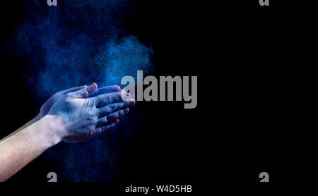 Hands clapping with blue holi powder on black Stock Photo