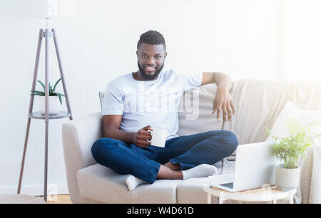 Cheerful african man enjoying rest at home office Stock Photo