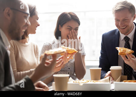 Happy asian worker laugh hold slice eating pizza with colleagues Stock Photo