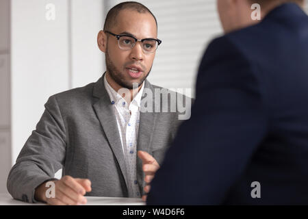 Serious african bank insurance broker lawyer in suit consulting client Stock Photo