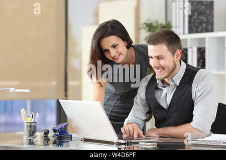 Happy boss teaching intern using a laptop at office Stock Photo