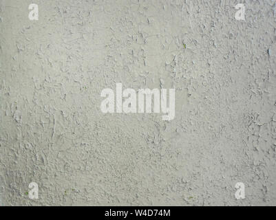 Grey paint peeling on a metallic surface background. Old grungy, weathered painted wall texture. Cracked, dirty, silver plaster falling off the constr Stock Photo