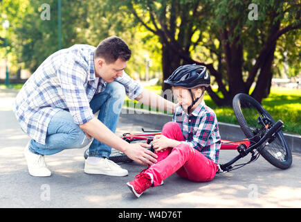 Father is comforting his girl after falling from bicycle Stock Photo