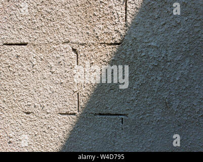 Old grey stone masonry wall texture made of foam blocks or airblocks split on two sides light and shadow. Abstract plastered surface. Grunge, weathere Stock Photo