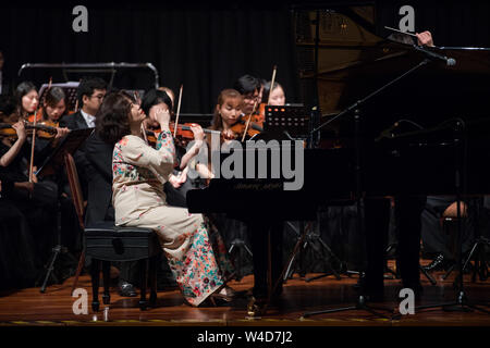 (190722) -- KUALA LUMPUR, July 22, 2019 (Xinhua) -- Malaysian pianist Claudia Yang (front) performs during the 'Maritime Silk Road Legend Concert 2019' in Kuala Lumpur, Malaysia, July 16, 2019. 'When hearing the Yellow River Piano Concerto for the first time, I was deeply moved,' Malaysian pianist Claudia Yang remembers vividly the scene after more than three decades. 'Looking back, I feel incredible. I was only 12 years old, but I could feel the blood was boiling inside me,' she recalled in an interview with Xinhua. TO GO WITH 'Feature: A Malaysian pianist's musical bond with China' (Xinh Stock Photo