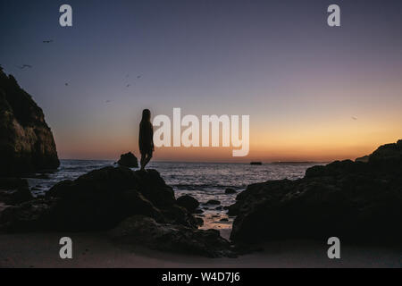 Young woman silhouetted against an orange sunset Stock Photo
