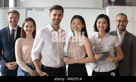 Happy diverse professional leaders looking at camera stand with employees Stock Photo