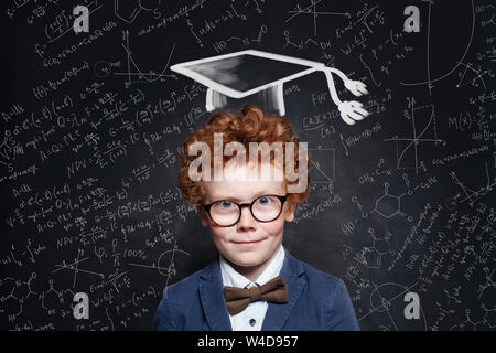 Smart kid student in graduation hat on chalkboard background. Back to school portrait Stock Photo