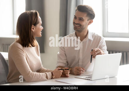 Male and female colleagues talking working together sit at desk Stock Photo