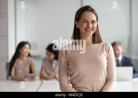 Cheerful young female leader looking at camera in corporate office Stock Photo