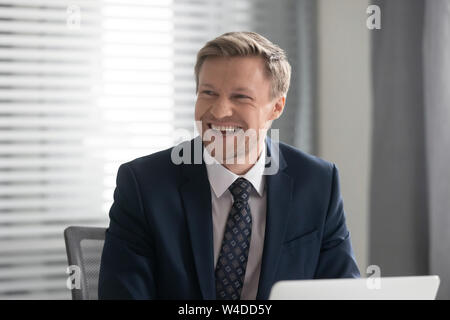 Happy cheerful businessman in suit laughing sit at work desk Stock Photo