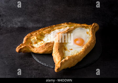 Traditional Adjarian Georgian khachapuri with cheese and egg on black background. Stock Photo