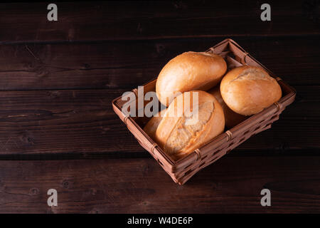 Buns in bread basket on a wooden background, low key, rustic Stock Photo
