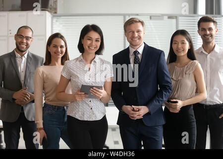 Diverse professional business leaders posing with multicultural workers in office Stock Photo