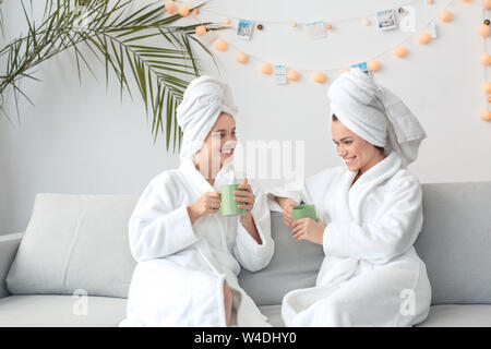 Friends together at home beauty care sitting in towels drinking coffee talking cheerful Stock Photo