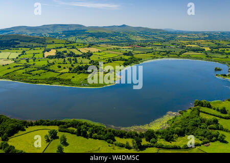 Aerial view of a lake surrounded by green, rolling farmland (Llangorse Lake, Wales) Stock Photo