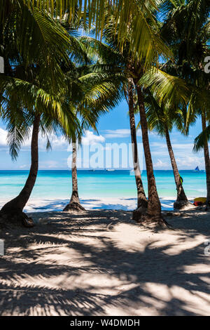 A beautiful tropical sandy beach surrounded by palm trees and warm ocean (White Beach, Boracay) Stock Photo