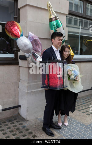 Hillary Chung (right), a 21 year-old Law graduate from Hong Kong, celebrates her graduation with a 2:1 degree outside the London School of Economics (LSE) after her graduation ceremony, on 22nd July 2019, in London, England. Stock Photo