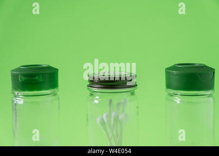 3 Glass spice jars on lime green background with blank empty room space for text or copy. Three kitchen bottles recycled and reused to store cotton sw Stock Photo