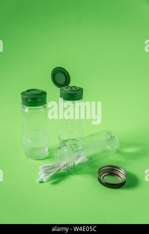 3 Glass spice jars on lime green background with blank empty room space for text or copy. Three kitchen bottles recycled and reused to store cotton sw Stock Photo