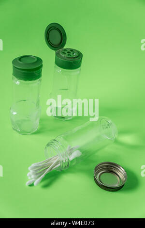 3 Glass spice jars on lime green background with blank empty room space for text or copy. Three kitchen bottles recycled and reused to store cotton sw Stock Photo