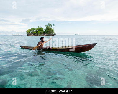 Island and local fisherman in dug out canoe in New Georgia group, Western Province, Solomon Islands, South Pacific Stock Photo