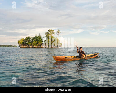 Island and local fisherman in dug out canoe in New Georgia group, Western Province, Solomon Islands, South Pacific Stock Photo