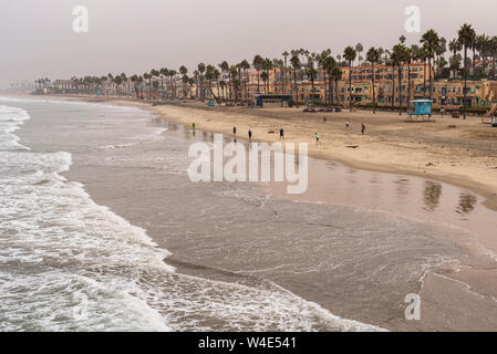 Looking down at coastline with ocean waves and beach with vacation homes, apartments and condominiums along the beach with tall palm trees. Stock Photo