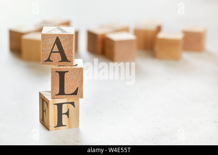 Three wooden cubes with letters ALF means Always Listen First , on white table, more in background, space for text in right down corner Stock Photo