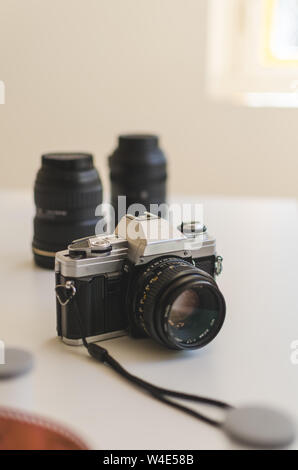 Vertical view of a vintage 35mm analogue camera surrounded with lenses and film on a table.  Analogue photography concept Stock Photo