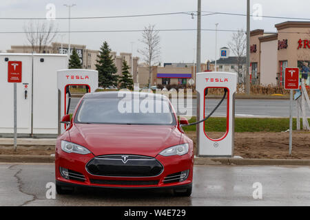 Front of Red Tesla Model S supercharging in Mississauga at Tesla Supercharger Station. Stock Photo