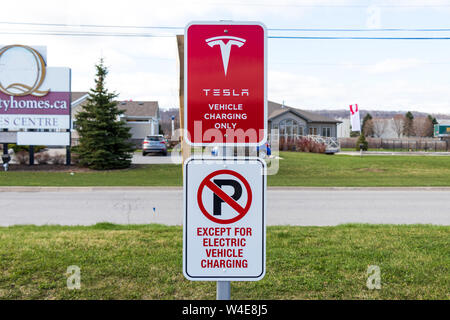 'Tesla Vehicle Charging Only' and 'No Parking Except For Electric Vehicle Charging' sign at Tesla Supercharger Station. Stock Photo