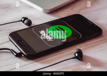 Nizhyn, Ukraine/July-16-2019: Smartphone with Spotify music application and headphones Stock Photo