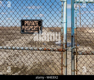 Chain link fence gates chained and locked with no trespassing, private property sign at the site of an abandoned and razed factory Stock Photo