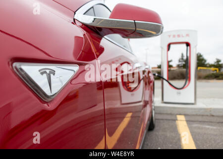 Red Tesla Model S side-view as the vehicle is supercharged at Tesla CF Markham Supercharger. Stock Photo