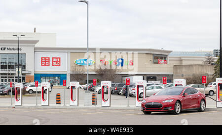 Red Tesla Model S supercharging at the Tesla Supercharger in-front CF Markham Shopping Centre. Stock Photo