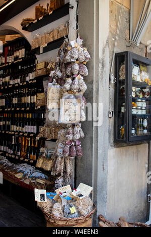 Wine shop in Cortana, Italy selling wine, olive oil, dried pasta, rice, jams, risotto and various meats and salami's that hang outside the store Stock Photo