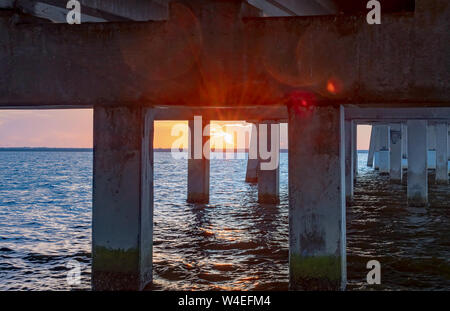 View of the sunrise under the bridge over the water Stock Photo