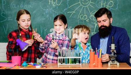 Little kids learning chemistry in school laboratory. school kids scientist studying science. happy children teacher. back to school. students doing science experiments with microscope in lab. Stock Photo