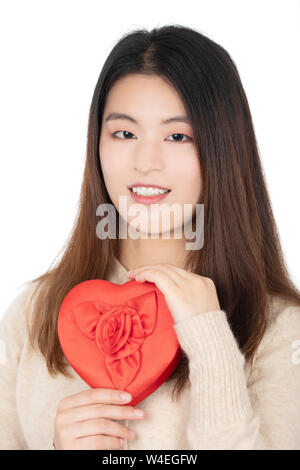 Beautiful Chinese American woman enjoying a special gift of a box of chocolates in a red heart isolated on a white background Stock Photo