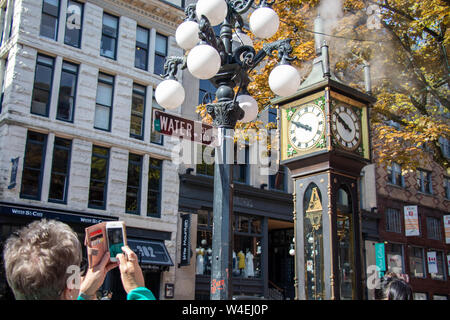 Women takes photo of world famous Gastown Steam Clock in Vancouver, BC on Water St. Stock Photo