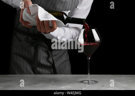 red wine pouring in glass. bartender on waiter concept on black background. Stock Photo